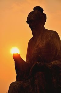 Old statue against clear sky during sunset