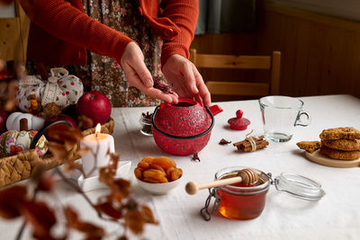 Cozy autumn days. woman brew tea in red teapot on the table with linen tablecloth. fall mood. 