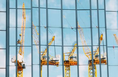 Reflection of cranes in modern glass building