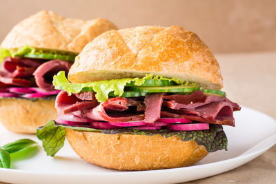 Ready-to-eat hamburger with pastrami, vegetables and basil on a plate on craft paper