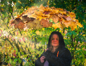 Female model holds an umbrella with autumn leaves on it in hand to the autumn beginning