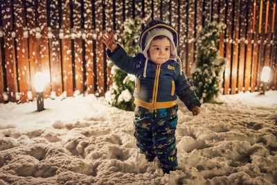 Boy walking on snow in yard at night