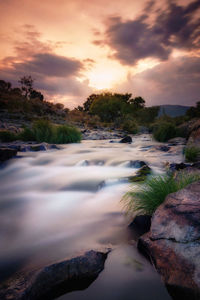 Scenic view of waterfall against sky during sunset