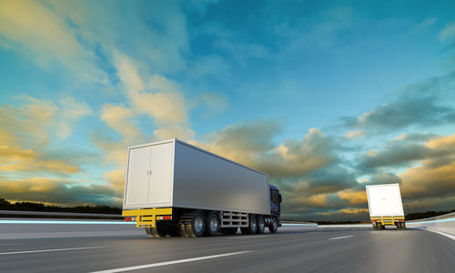 Vehicles on road against sky during sunset