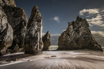 Rock formation by sea against sky