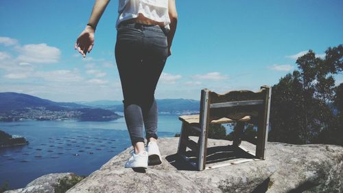 Low section of woman standing on sea shore against sky