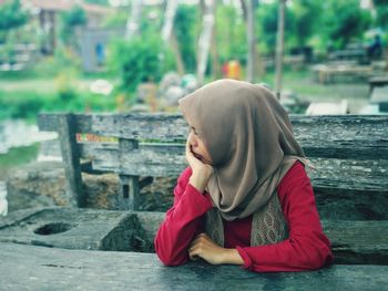Side view of woman sitting outdoors