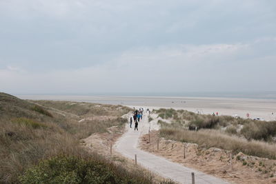 People at sandy beach against sky