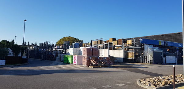 Road by buildings against clear blue sky