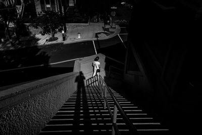 Rear view of a person walking down a staircase and long shadows