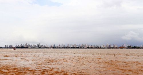 Sailboats in sea by buildings against sky