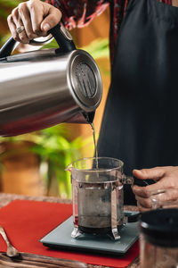 Midsection of woman making coffee in cafe