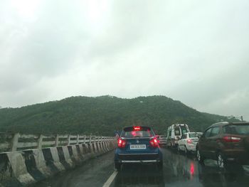 Vehicles on road against sky during rainy season