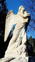 Low angle view of angel statue against clear blue sky