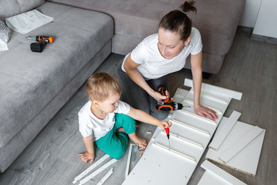 High angle view of mother and son working on wood at home