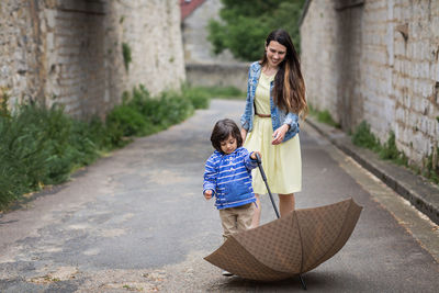Mother and little handsome baby boy playing with umbrella outdoor