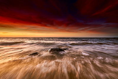 Scenic view of sea against dramatic sky during sunset