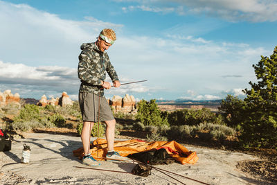 Stylish male camper sets up tent in the deserts of utah