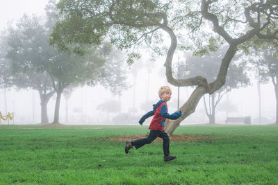 Full length of boy running against tree at park