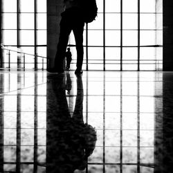 Low section of silhouette man walking on tiled floor