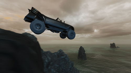 Vintage car on rock by sea against sky