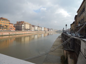 Bridge over river amidst buildings in city against sky