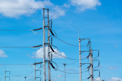 Low angle view of electricity pylon against blue sky