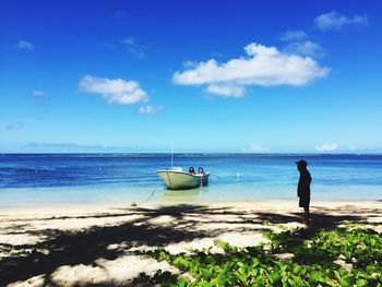 Man standing on beach next to boat