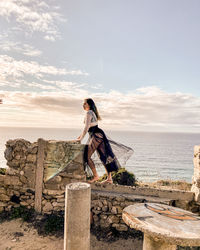 Woman standing by sea against sky