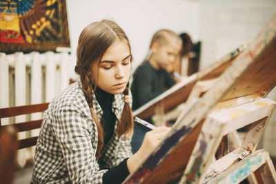 Young woman looking away while sitting on wood