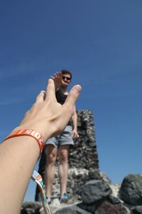 Low angle view of woman standing against blue sky