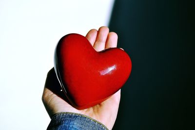 Close-up of hand holding heart shape against white background