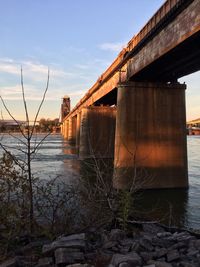 Abandoned bridge over river against sky