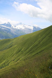 Scenic view of green landscape and mountains against sky