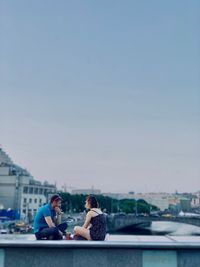 People sitting in city against clear sky
