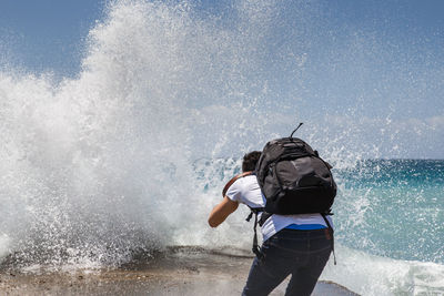 Man with umbrella standing in sea against sky