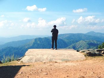 Rear view of man standing on mountain against sky