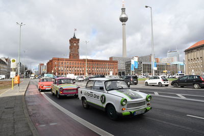 Cars on city street against cloudy sky