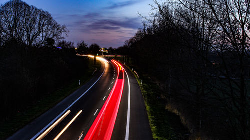 Light trails on road against sky at night