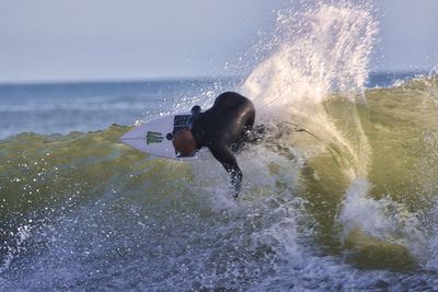 Man splashing water in sea against sky