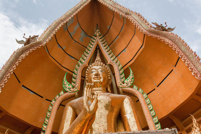 Low angle view of buddha statue in temple against sky