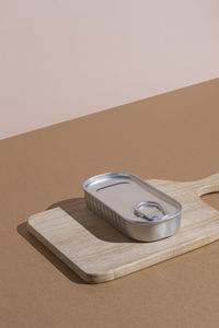 High angle of metal tin with preserved food on wooden cutting board