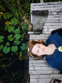 Directly above portrait of girl lying on pier over pond