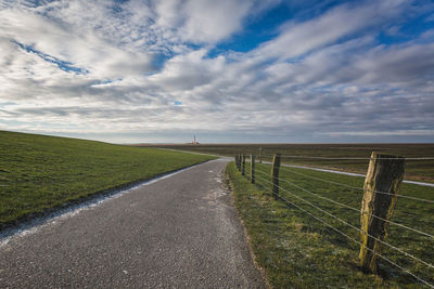 Road amidst field against sky