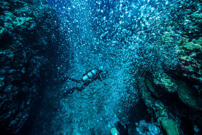 Scuba divers swimming by bubbles in sea