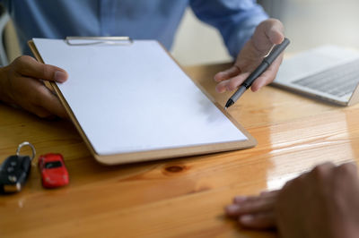 Midsection of man using mobile phone on table