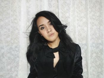 Portrait of fashionable young woman against curtain at home