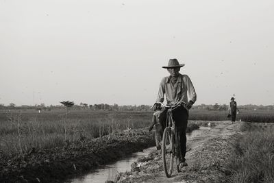 Man riding motorcycle on field against clear sky