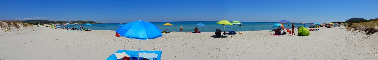 Group of people on beach against blue sky