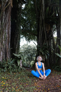 A beautiful girl with light hair is practicing yoga or meditation in the park